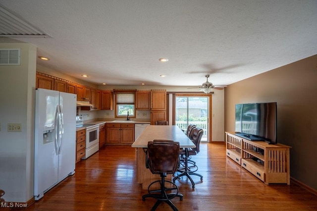 1565 Lois St, Belpre, OH 45714 - kitchen with white appliances, light countertops, under cabinet range hood, dark wood finished floors, and a kitchen island