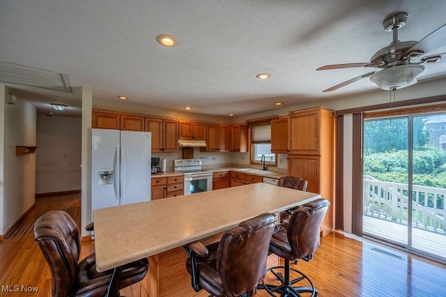1565 Lois St, Belpre, OH 45714 - kitchen with white appliances, under cabinet range hood, light wood-type flooring, light countertops, and ceiling fan