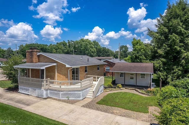 1565 Lois St, Belpre, OH 45714 - view of front of home with brick siding, an outdoor structure, a front lawn, a deck, and a chimney