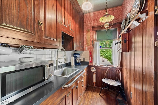 10921 Wade Park Ave, Cleveland, OH 44106 - kitchen with stainless steel microwave, light wood-style flooring, tasteful backsplash, dark countertops, and decorative light fixtures