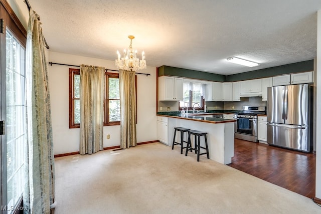 3613 Peninsula Dr, Akron, OH 44319 - kitchen featuring stainless steel appliances, dark countertops, dark colored carpet, a chandelier, and a textured ceiling