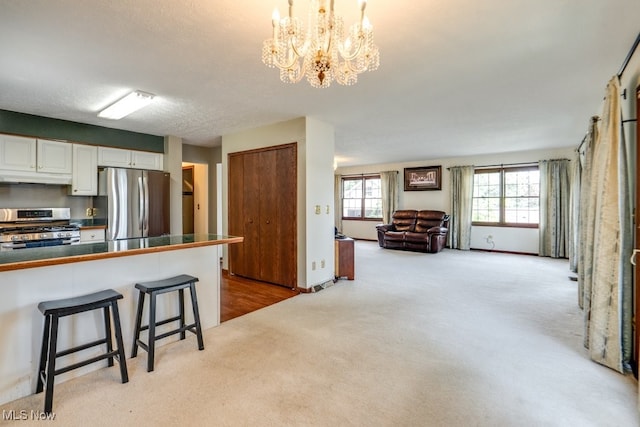 3613 Peninsula Dr, Akron, OH 44319 - kitchen featuring appliances with stainless steel finishes, light colored carpet, under cabinet range hood, a kitchen bar, and white cabinets