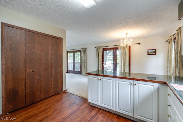 3613 Peninsula Dr, Akron, OH 44319 - kitchen with a chandelier, dark wood finished floors, white cabinets, a peninsula, and a textured ceiling