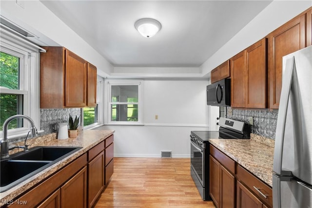 3788 Manchester Rd, Coventry, OH 44319 - kitchen featuring stainless steel appliances, light wood finished floors, decorative backsplash, and brown cabinetry