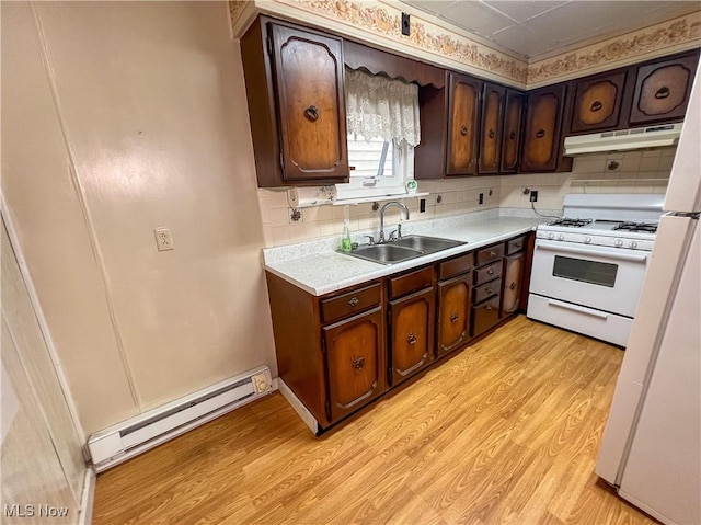1030 Saint George St, East Liverpool, OH 43920 - kitchen featuring baseboard heating, gas range gas stove, under cabinet range hood, light countertops, and tasteful backsplash