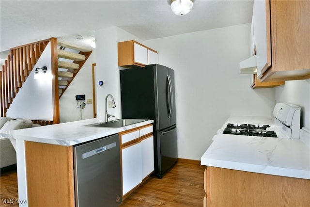 3189 Woodland Trl Unit A, Cortland, OH 44410 - kitchen with stainless steel dishwasher, white range with gas stovetop, under cabinet range hood, a peninsula, and light countertops