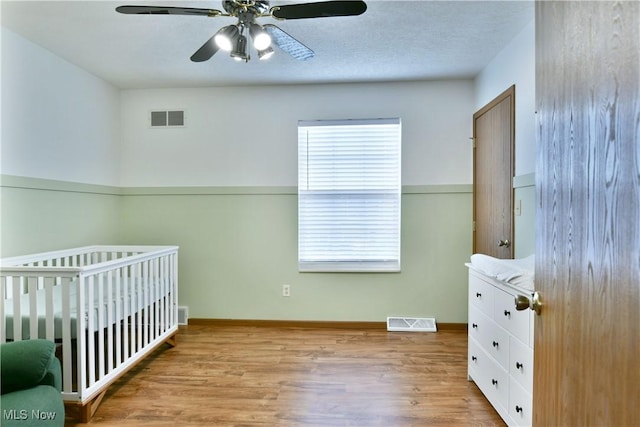 3189 Woodland Trl Unit A, Cortland, OH 44410 - unfurnished bedroom with wood finished floors, a crib, and a ceiling fan
