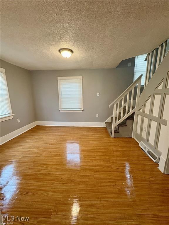 309 Emma St, Niles, OH 44446 - unfurnished living room featuring stairway, a textured ceiling, and wood finished floors