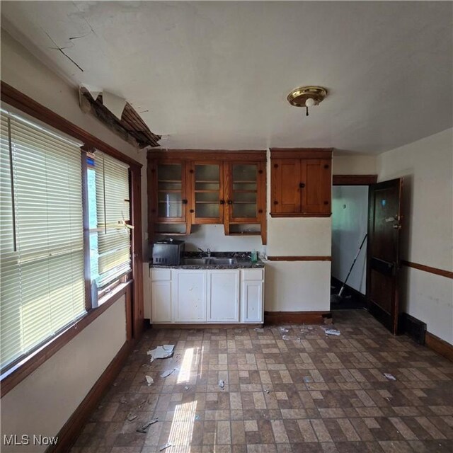 13013 Soika Ave, Cleveland, OH 44120 - kitchen with dark countertops, glass insert cabinets, brick patterned floors, and brown cabinets