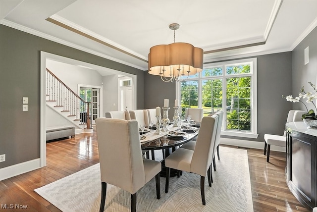 3880 Waterford Ct, Orange, OH 44122 - dining room featuring a tray ceiling, crown molding, wood finished floors, stairway, and a chandelier