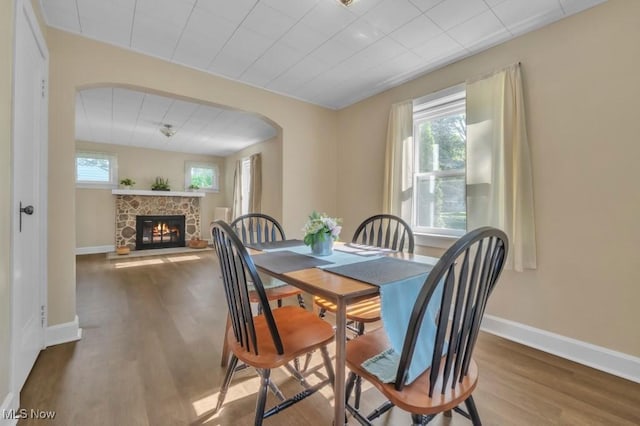 4706 Lansing Dr, North Olmsted, OH 44070 - dining space featuring wood finished floors, a stone fireplace, and arched walkways