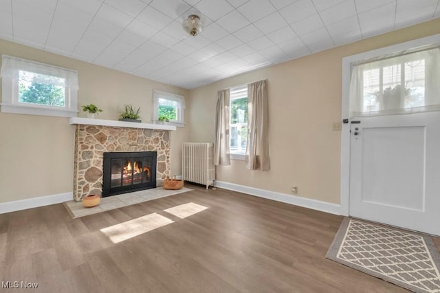 4706 Lansing Dr, North Olmsted, OH 44070 - unfurnished living room featuring radiator heating unit, a stone fireplace, and wood finished floors