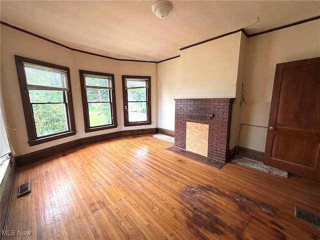1709 Washington Blvd, Belpre, OH 45714 - unfurnished living room with crown molding, a brick fireplace, and hardwood / wood-style flooring