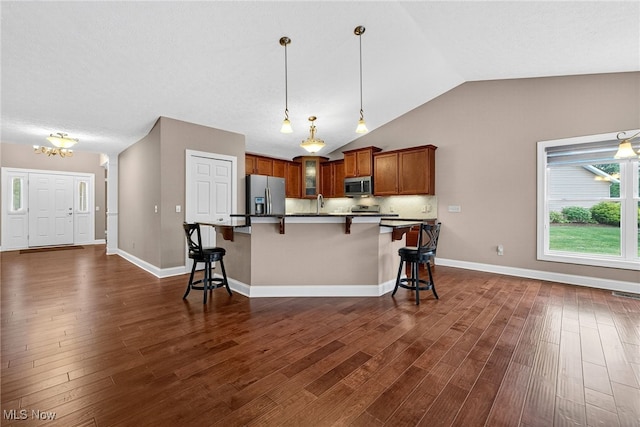 498 Water Pointe Ln, Brunswick, OH 44212 - kitchen featuring stainless steel appliances, a breakfast bar, brown cabinetry, dark wood-type flooring, and vaulted ceiling