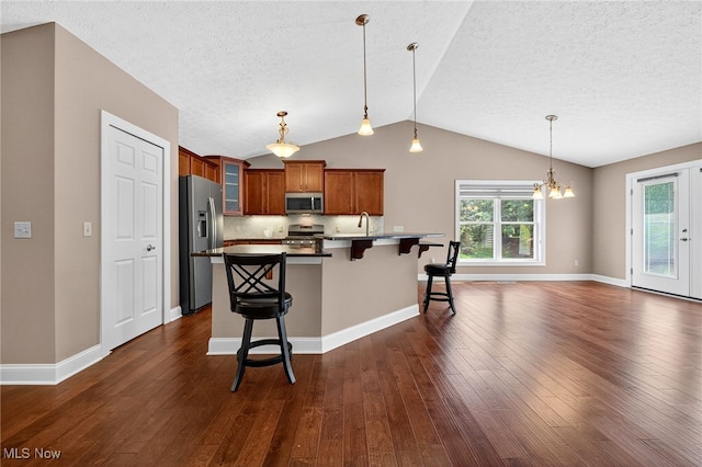 498 Water Pointe Ln, Brunswick, OH 44212 - kitchen featuring stainless steel appliances, vaulted ceiling, brown cabinetry, a breakfast bar area, and glass insert cabinets