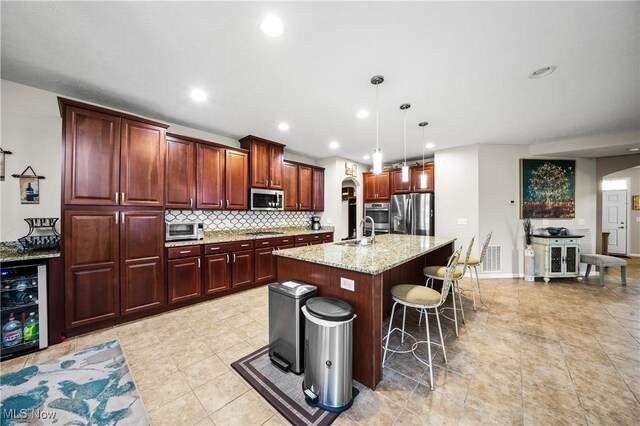 8028 Megan Meadow Dr, Hudson, OH 44236 - kitchen with appliances with stainless steel finishes, arched walkways, beverage cooler, light stone counters, and pendant lighting