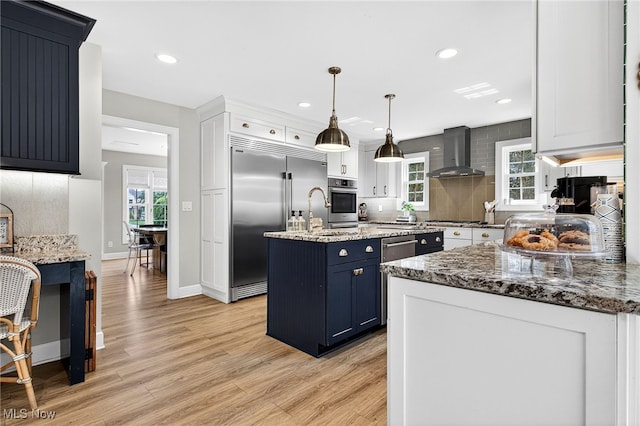 14370 Washington Blvd, University Heights, OH 44118 - kitchen with wall chimney exhaust hood, appliances with stainless steel finishes, backsplash, light wood-type flooring, and light stone countertops
