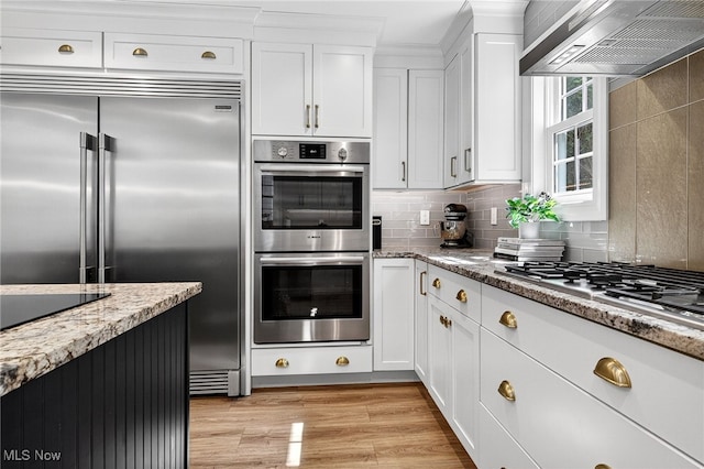 14370 Washington Blvd, University Heights, OH 44118 - kitchen with appliances with stainless steel finishes, ventilation hood, white cabinets, decorative backsplash, and light stone countertops