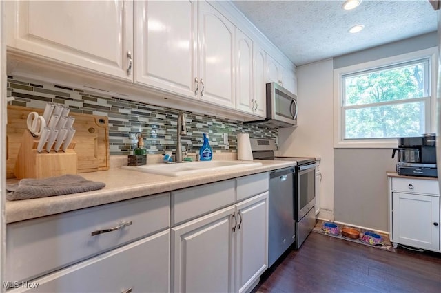4950 Trafalgar St SW, Canton, OH 44706 - kitchen featuring appliances with stainless steel finishes, white cabinets, backsplash, dark wood-style flooring, and a textured ceiling