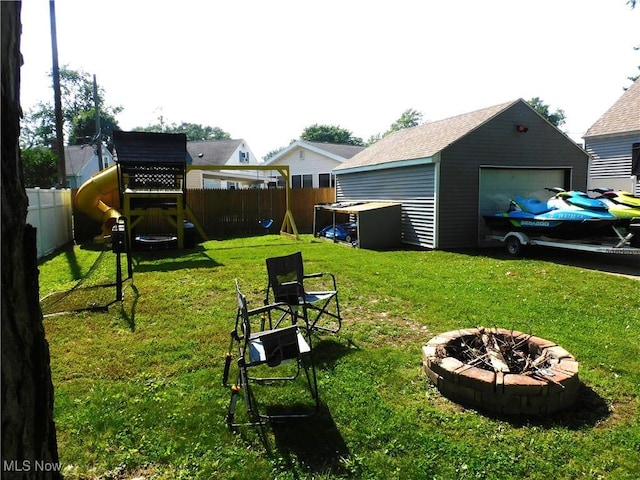 2804 Avon Blvd, Ashtabula, OH 44004 - fenced backyard with a playground, an outdoor fire pit, a garage, and an outbuilding