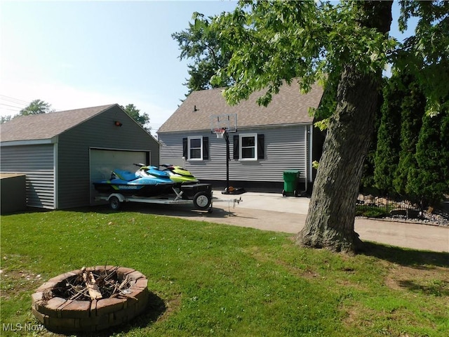 2804 Avon Blvd, Ashtabula, OH 44004 - back of house with a lawn, a detached garage, an outbuilding, an outdoor fire pit, and a shingled roof