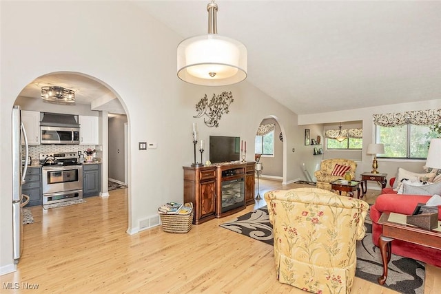 7148 N Brewster Pl, Concord, OH 44077 - living room with arched walkways, light wood-style floors, and lofted ceiling
