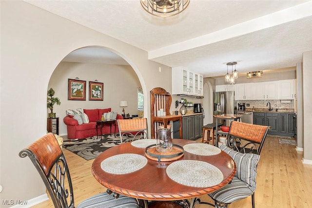 7148 N Brewster Pl, Concord, OH 44077 - dining room with arched walkways, light wood-type flooring, and a chandelier