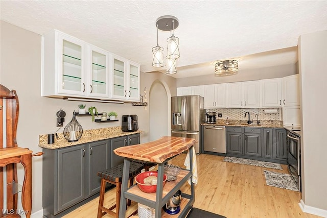 7148 N Brewster Pl, Concord, OH 44077 - kitchen with stainless steel appliances, gray cabinets, white cabinetry, light wood-type flooring, and glass insert cabinets
