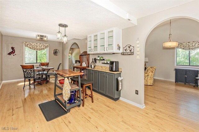 7148 N Brewster Pl, Concord, OH 44077 - kitchen featuring arched walkways, plenty of natural light, light wood-type flooring, and glass insert cabinets
