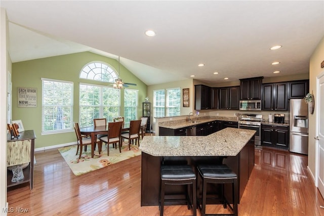 3139 Junior Pkwy, Brunswick, OH 44212 - kitchen featuring stainless steel appliances, light stone counters, wood finished floors, a center island, and lofted ceiling
