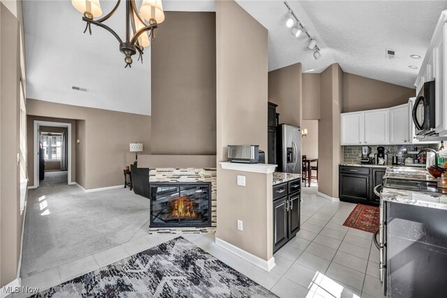 254 Vista Cir, North Olmsted, OH 44070 - kitchen featuring high vaulted ceiling, light tile patterned floors, rail lighting, white cabinets, and light stone countertops
