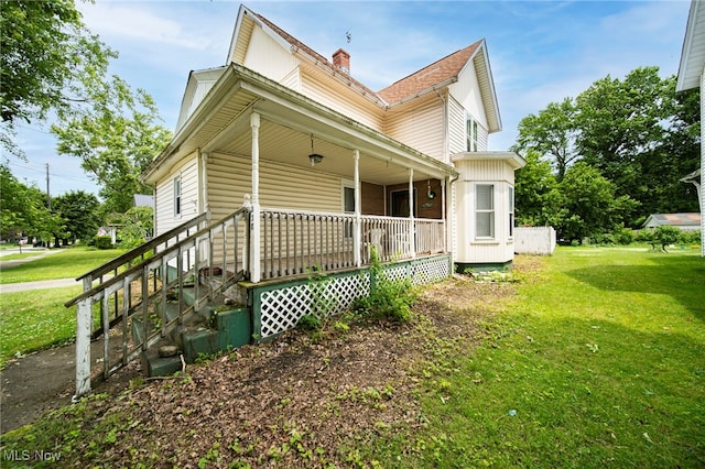238 Whitney St, Conneaut, OH 44030 - view of side of home featuring covered porch, a yard, and a chimney