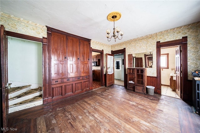 238 Whitney St, Conneaut, OH 44030 - unfurnished dining area with wallpapered walls, a chandelier, wood finished floors, and stairs