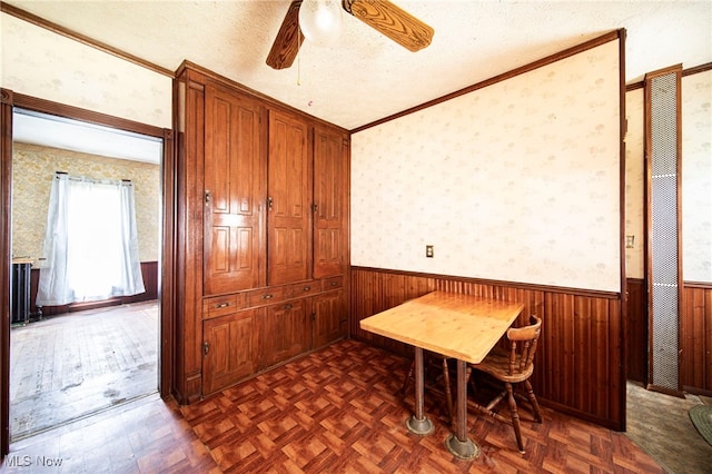 238 Whitney St, Conneaut, OH 44030 - unfurnished dining area featuring wainscoting, ceiling fan, wood walls, a textured ceiling, and crown molding