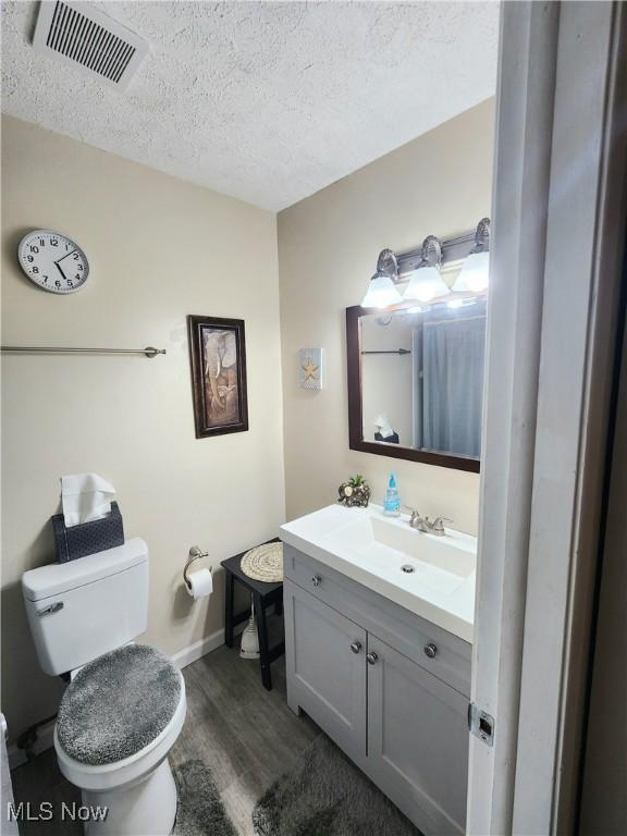 4211 Dennis Ln, Brunswick, OH 44212 - half bath featuring wood finished floors, vanity, and a textured ceiling