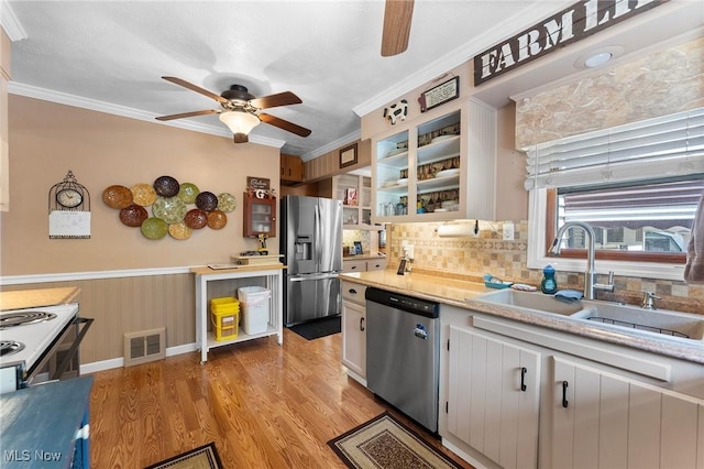4843 Summer Ln, Brooklyn, OH 44144 - kitchen featuring appliances with stainless steel finishes, a ceiling fan, ornamental molding, light wood-style flooring, and tasteful backsplash