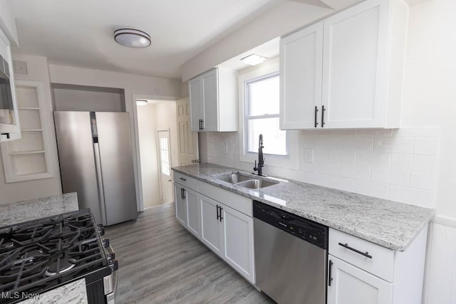 4033 Stonehaven Rd, South Euclid, OH 44121 - kitchen featuring appliances with stainless steel finishes, white cabinetry, backsplash, light stone countertops, and light wood-type flooring