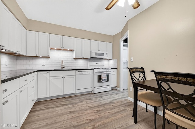 4183 Columbia Rd, North Olmsted, OH 44070 - kitchen featuring white appliances, a ceiling fan, light wood-type flooring, backsplash, and dark countertops