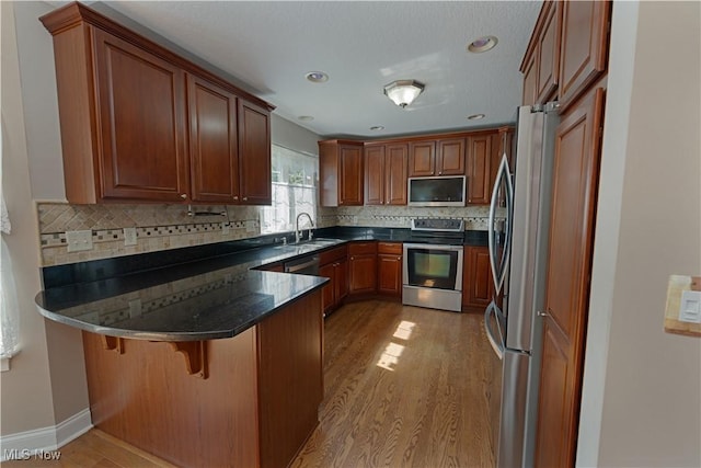 9812 Creekside Way, Streetsboro, OH 44241 - kitchen with appliances with stainless steel finishes, a peninsula, light wood-style floors, tasteful backsplash, and a kitchen breakfast bar