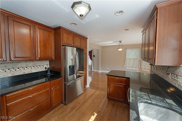 9812 Creekside Way, Streetsboro, OH 44241 - kitchen with stainless steel fridge, wood finished floors, brown cabinetry, tasteful backsplash, and dark stone counters