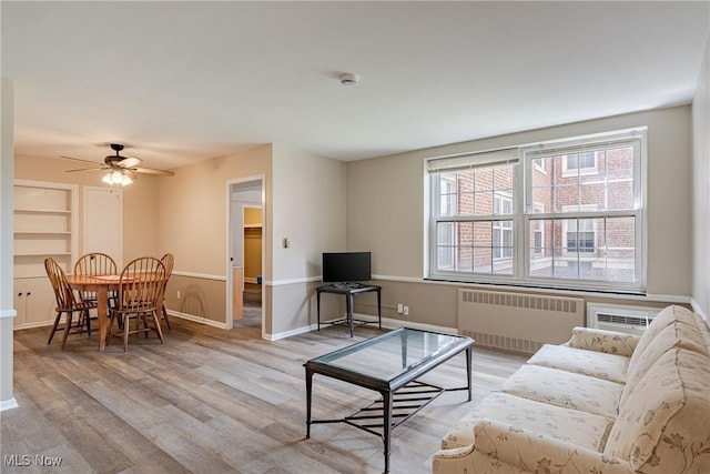 19201 Van Aken Blvd Unit 211, Shaker Heights, OH 44122 - living room with radiator heating unit, light wood-style flooring, a ceiling fan, and built in shelves