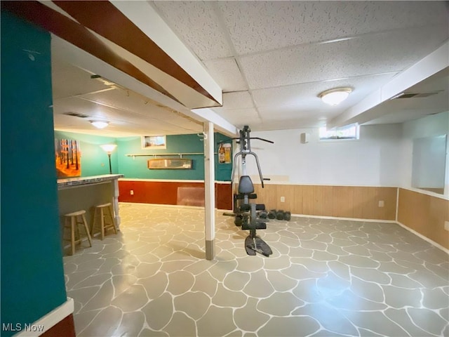 123 Prentiss St, Munroe Falls, OH 44262 - below grade area with a paneled ceiling, a dry bar, wainscoting, stone flooring, and wooden walls