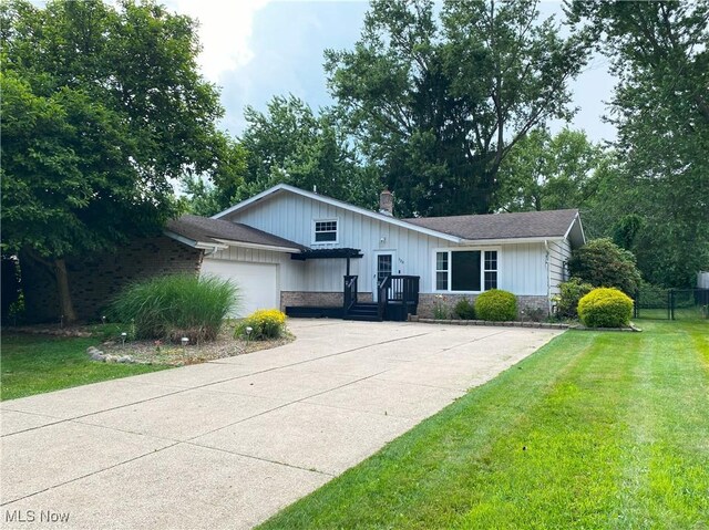123 Prentiss St, Munroe Falls, OH 44262 - view of front facade featuring a garage, driveway, stone siding, a chimney, and board and batten siding
