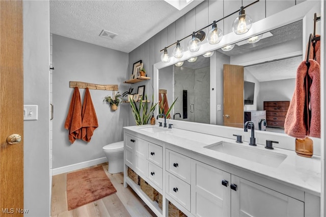 567 Westminster Cir, Akron, OH 44319 - bathroom featuring a textured ceiling, double vanity, wood finished floors, and an enclosed shower