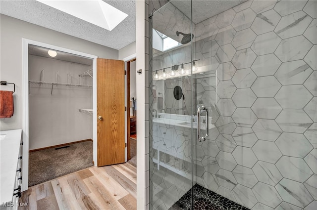 567 Westminster Cir, Akron, OH 44319 - full bathroom with a skylight, a stall shower, a textured ceiling, wood finished floors, and a spacious closet