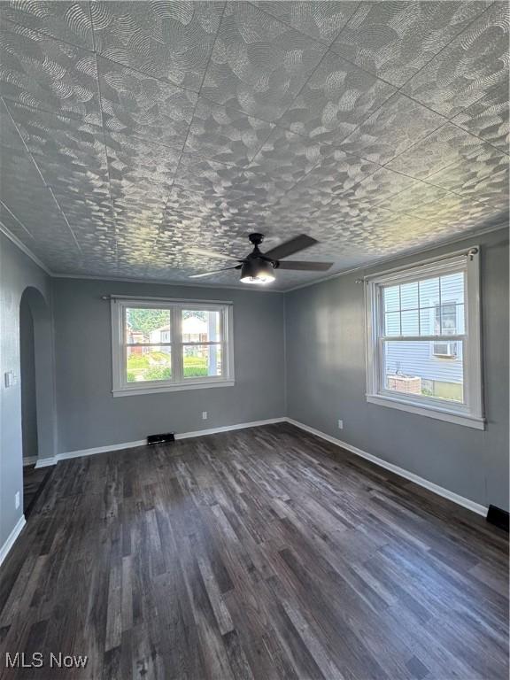 358 N 8th St, Coshocton, OH 43812 - empty room with arched walkways, dark wood-style flooring, ceiling fan, and plenty of natural light