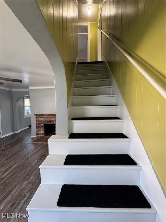358 N 8th St, Coshocton, OH 43812 - stairway with a fireplace, wood finished floors, ornamental molding, and arched walkways