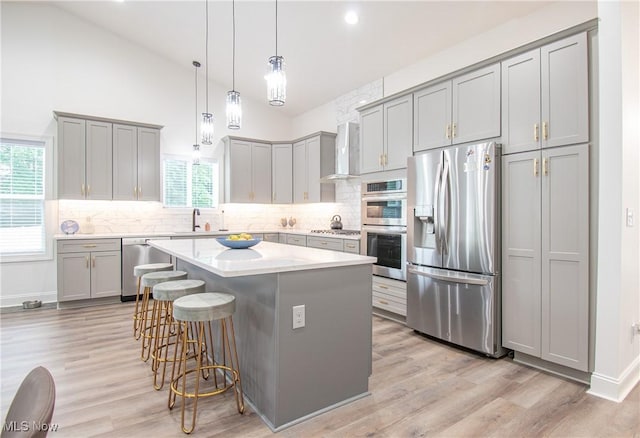 993 Pin Oaks Dr, Broadview Heights, OH 44147 - kitchen featuring appliances with stainless steel finishes, gray cabinetry, healthy amount of natural light, wall chimney range hood, and lofted ceiling