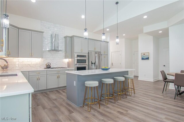 993 Pin Oaks Dr, Broadview Heights, OH 44147 - kitchen with wall chimney exhaust hood, stainless steel appliances, gray cabinets, a kitchen bar, and tasteful backsplash