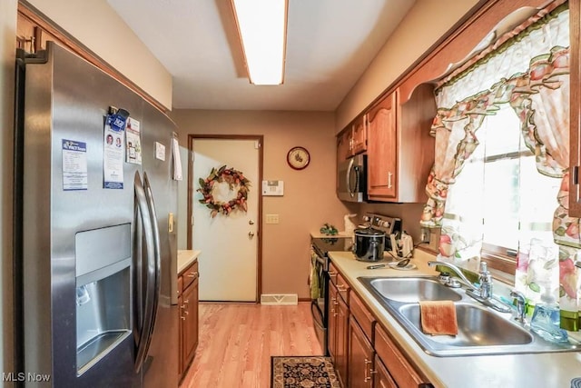 1769 Clearbrook Rd NW, Massillon, OH 44646 - kitchen with appliances with stainless steel finishes, brown cabinetry, light countertops, and light wood-style floors